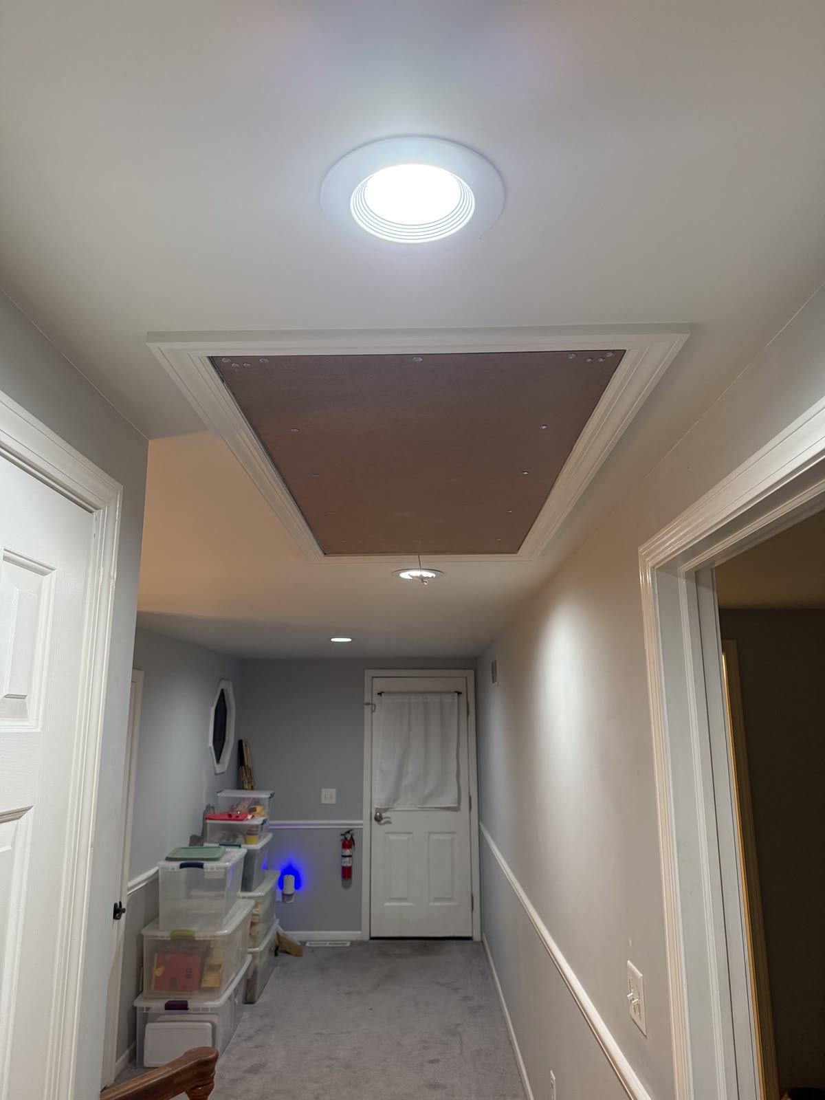 Finished attic access panel with painted trim casing in a hallway ceiling
