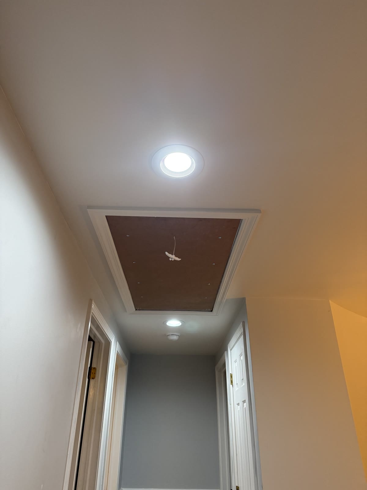 Finished attic access panel with painted trim casing in the hallway ceiling
