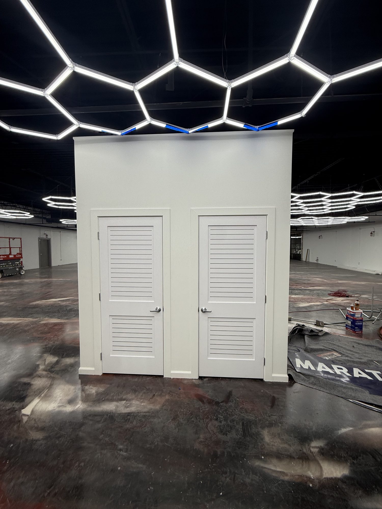 Freestanding drywall enclosure with louvered doors in an automotive showroom