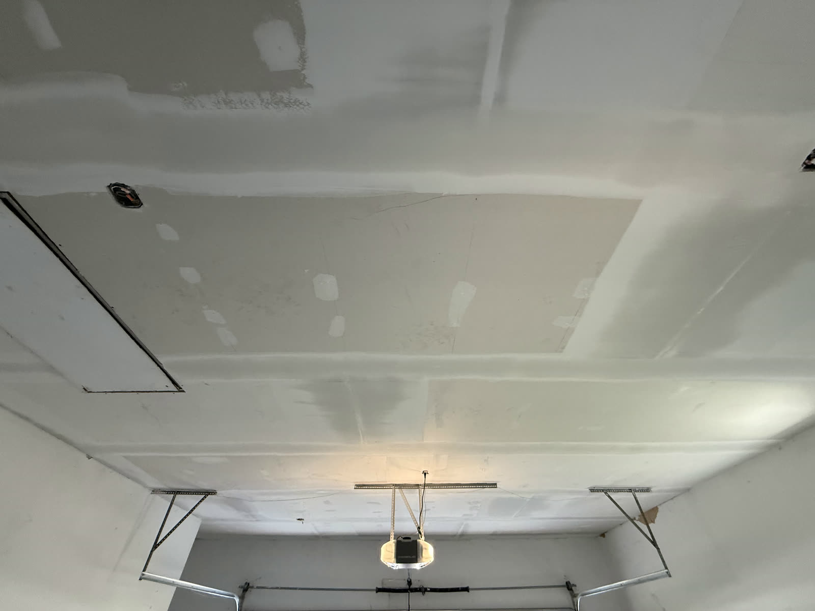 New drywall hung with seams taped and the attic hatch reframed.