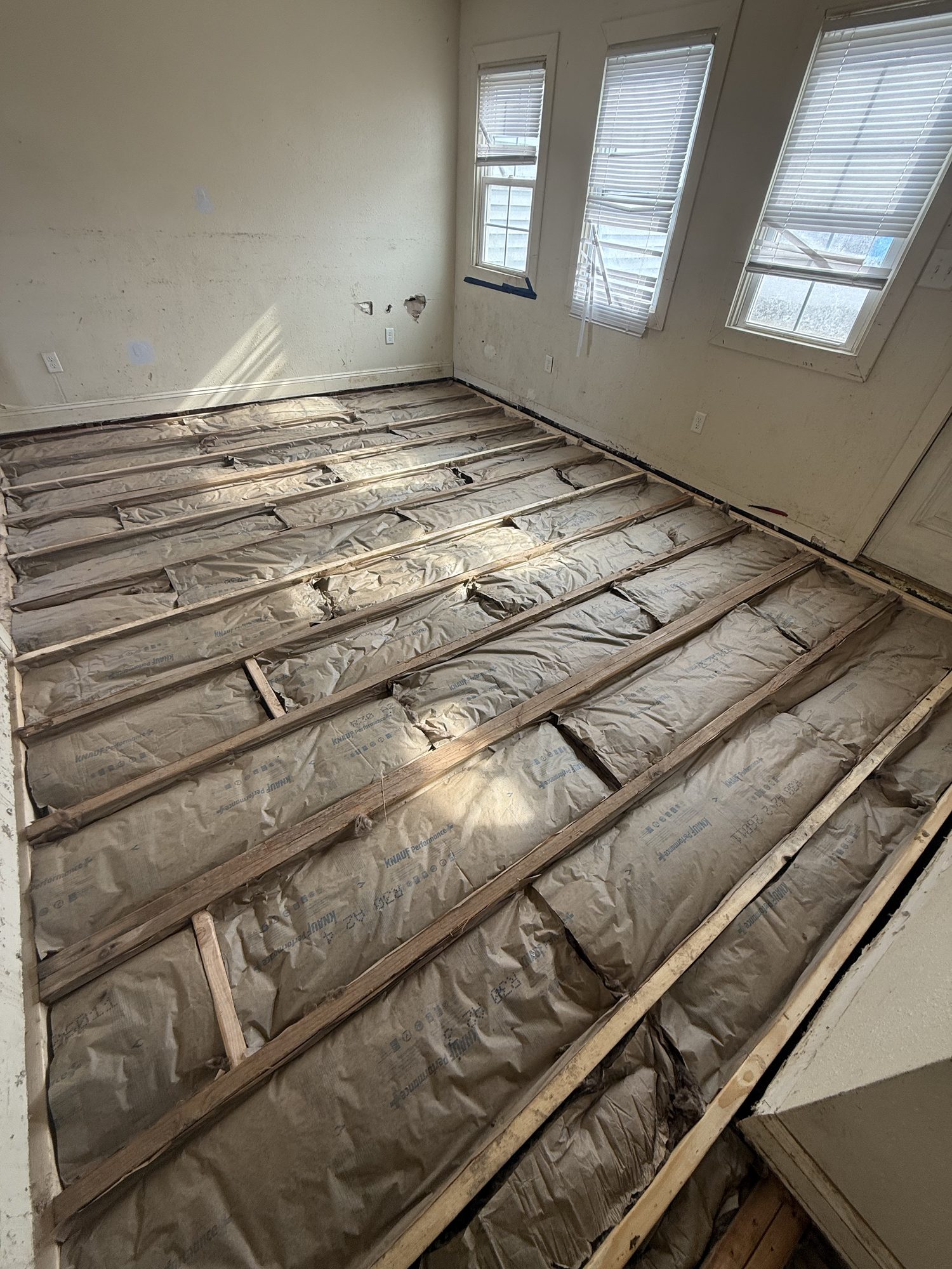 Insulation between floor joists during a Legacy Contracting Company project