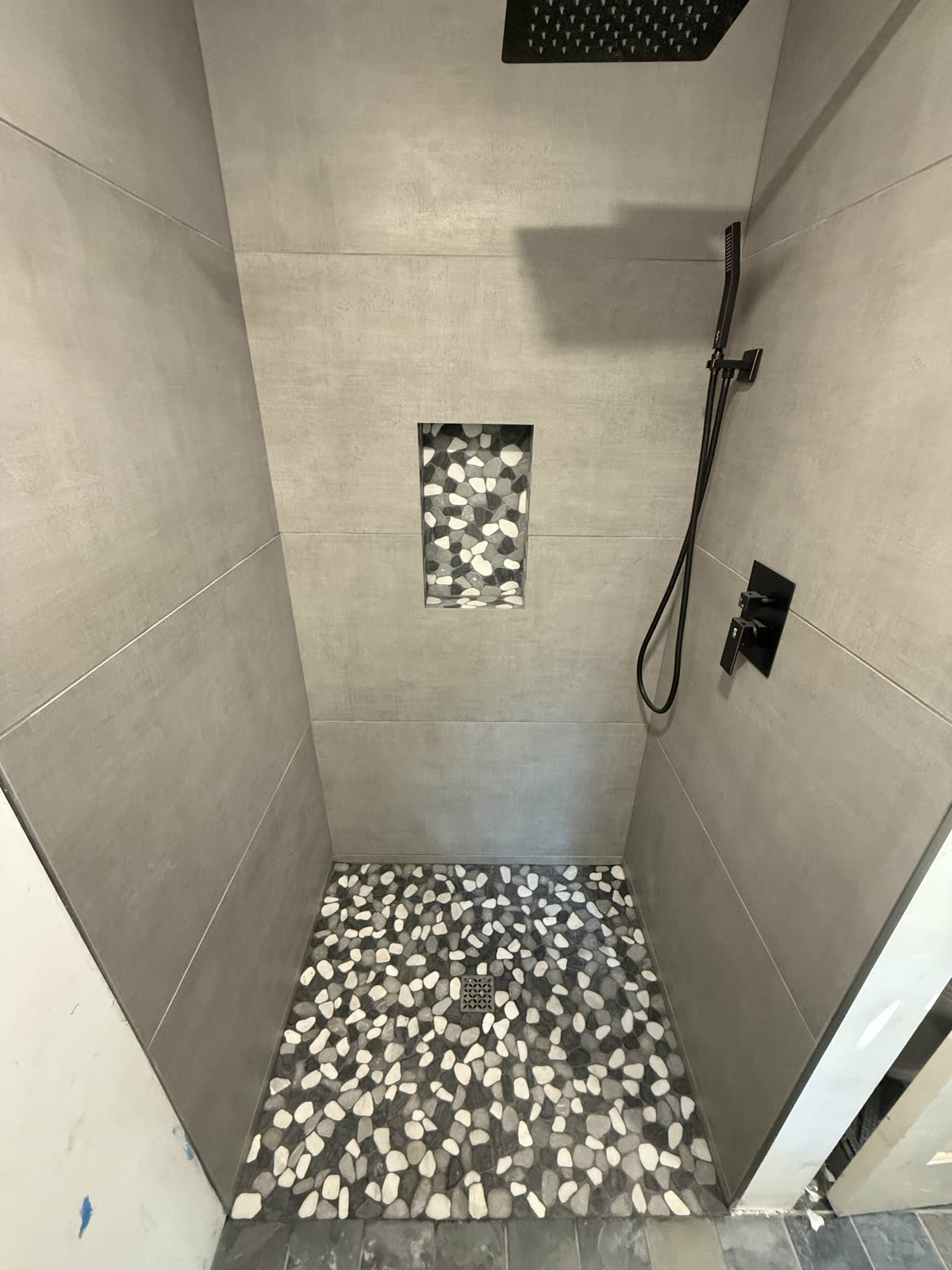 Custom gray tile shower with mosaic niche