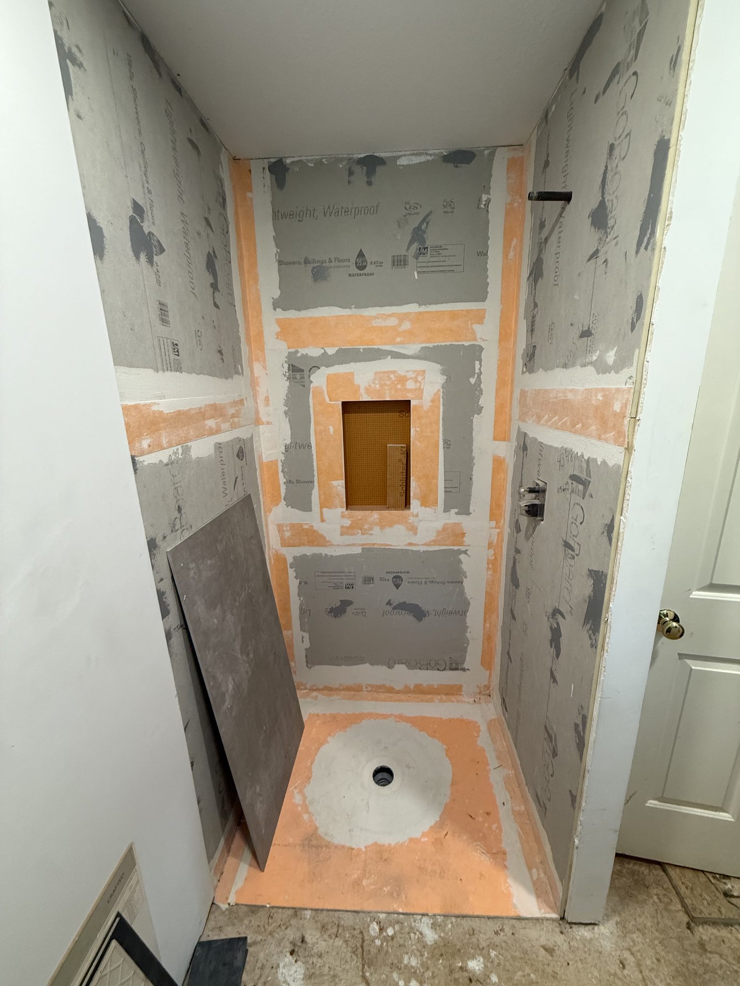 Custom gray tile shower with mosaic niche